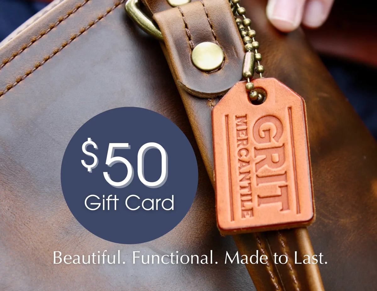 $50 Gift Card in navy circle design on top of a brown leather tote bag with "Grit Mercantile" imprinted on tan leather tag on antique brass ball chain. "Beautiful. Functional. Made to Last."